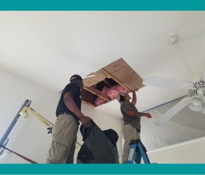 Our SERVPRO technicians working on removing the moisture and water from the ceiling.