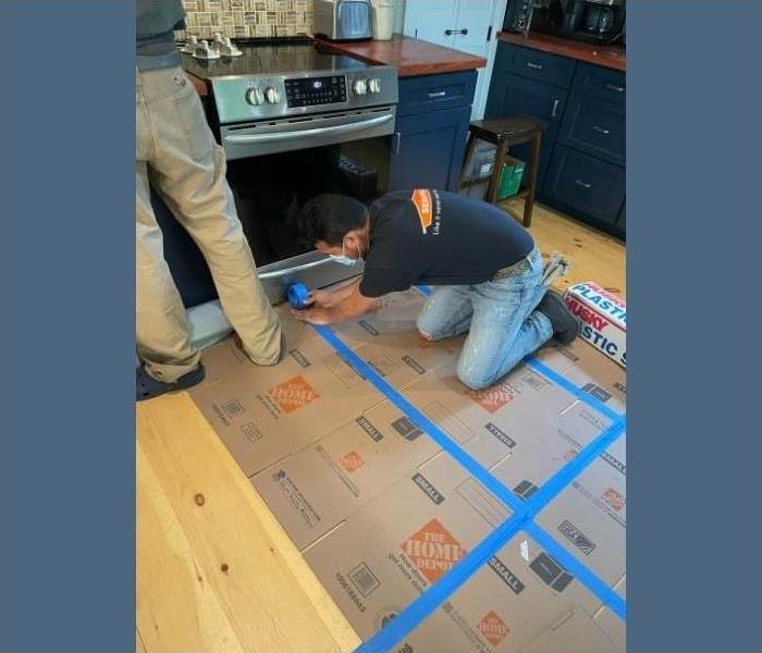 A SERVPRO technician laying down cardboard boxes to protect this Saratoga's home floors.