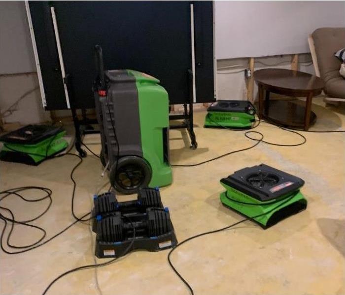 Several air movers and a dehumidifier drying out a Saratoga basement after a storm.