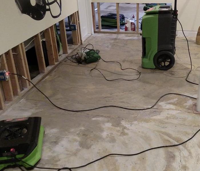 A basement with water stains being dried with SERVPRO equipment.